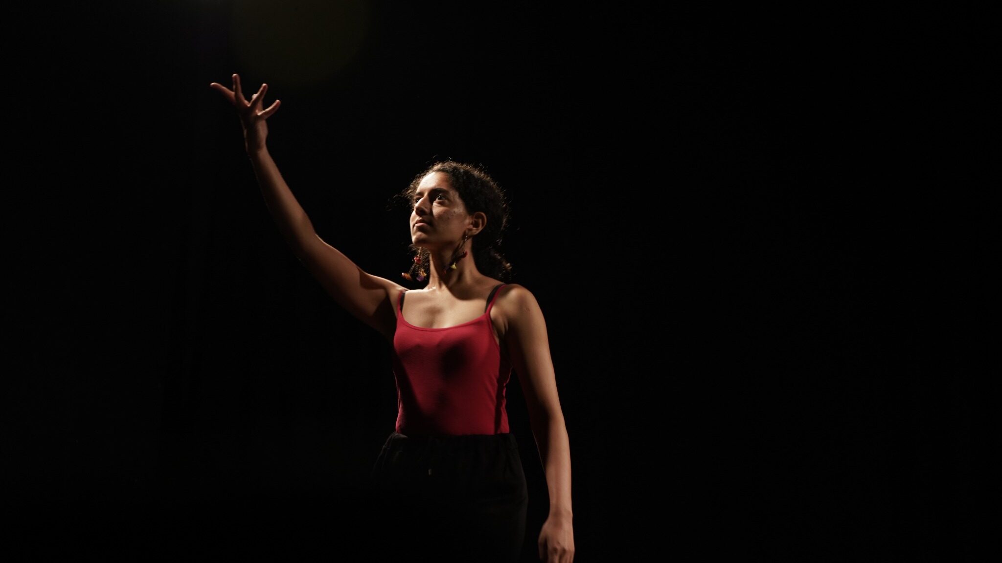 A performer standing in a pool of stage light in Harkat’s black box